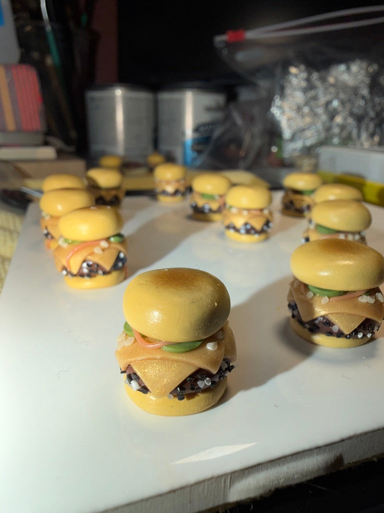 Small model hamburgers arranged on a white surface with a blurred background